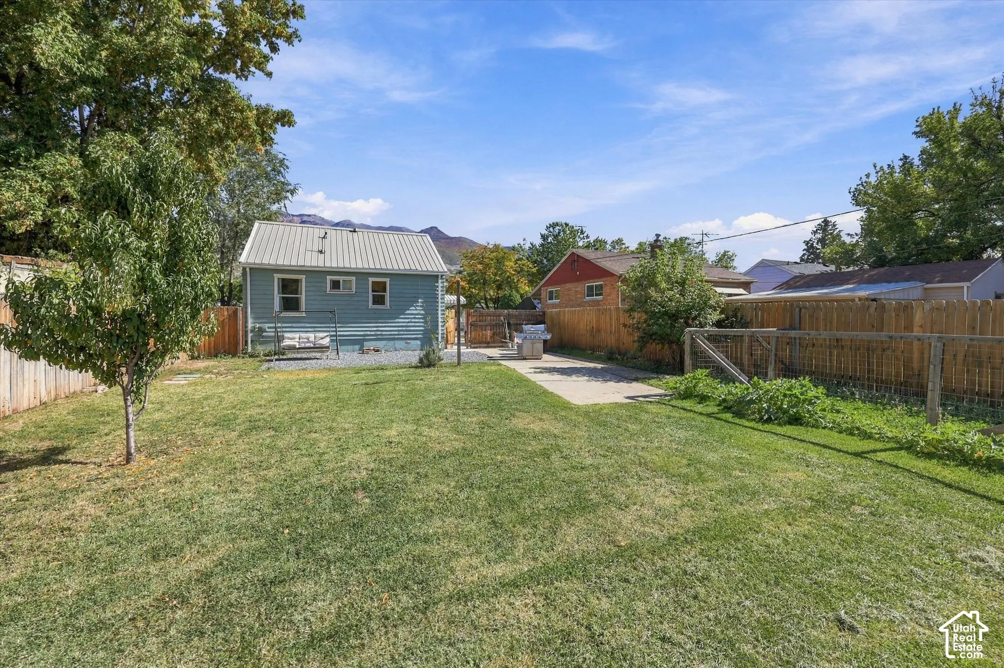 Expansive backyard with a manicured lawn, established trees, and wood fencing