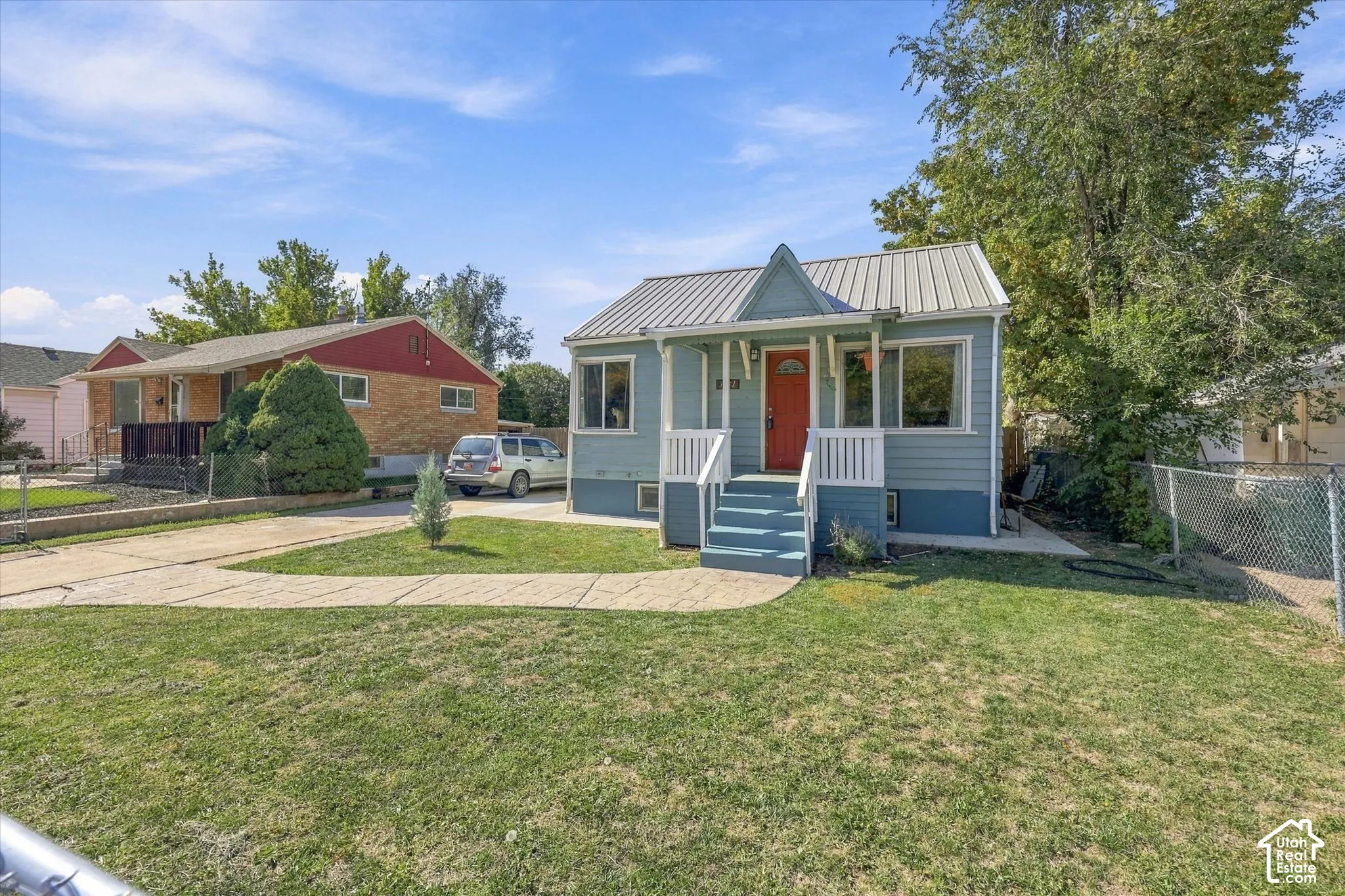 Light blue exterior with white trim, a metal roof, and an inviting red front door