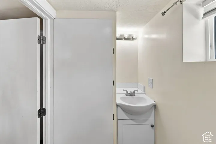 White vanity with integrated sink, chrome faucet, and overhead bar lighting fixture