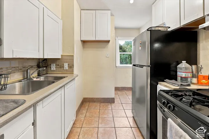 Modern white cabinetry, tile flooring, stainless steel sink, tile backsplash, and stainless steel appliances