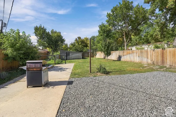 Expansive rear yard featuring a gravel area, concrete pathway, and a grass lawn