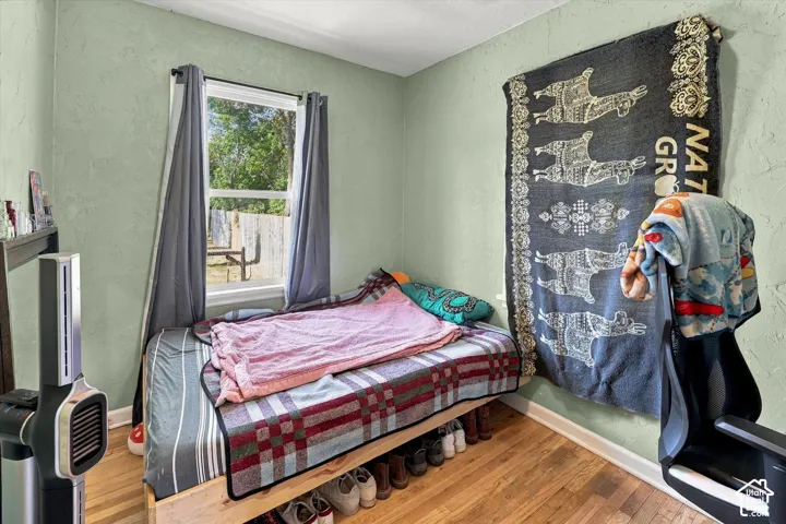 Wood-finish flooring with light green textured walls and a single window