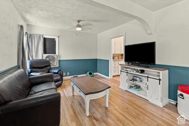 Hardwood flooring, painted wainscoting, ceiling fan, and an arched doorway