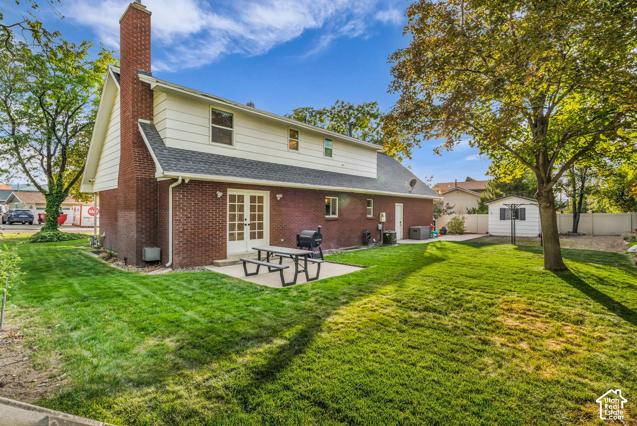 Rear exterior featuring brick and siding finishes, a prominent brick chimney, and a concrete patio
