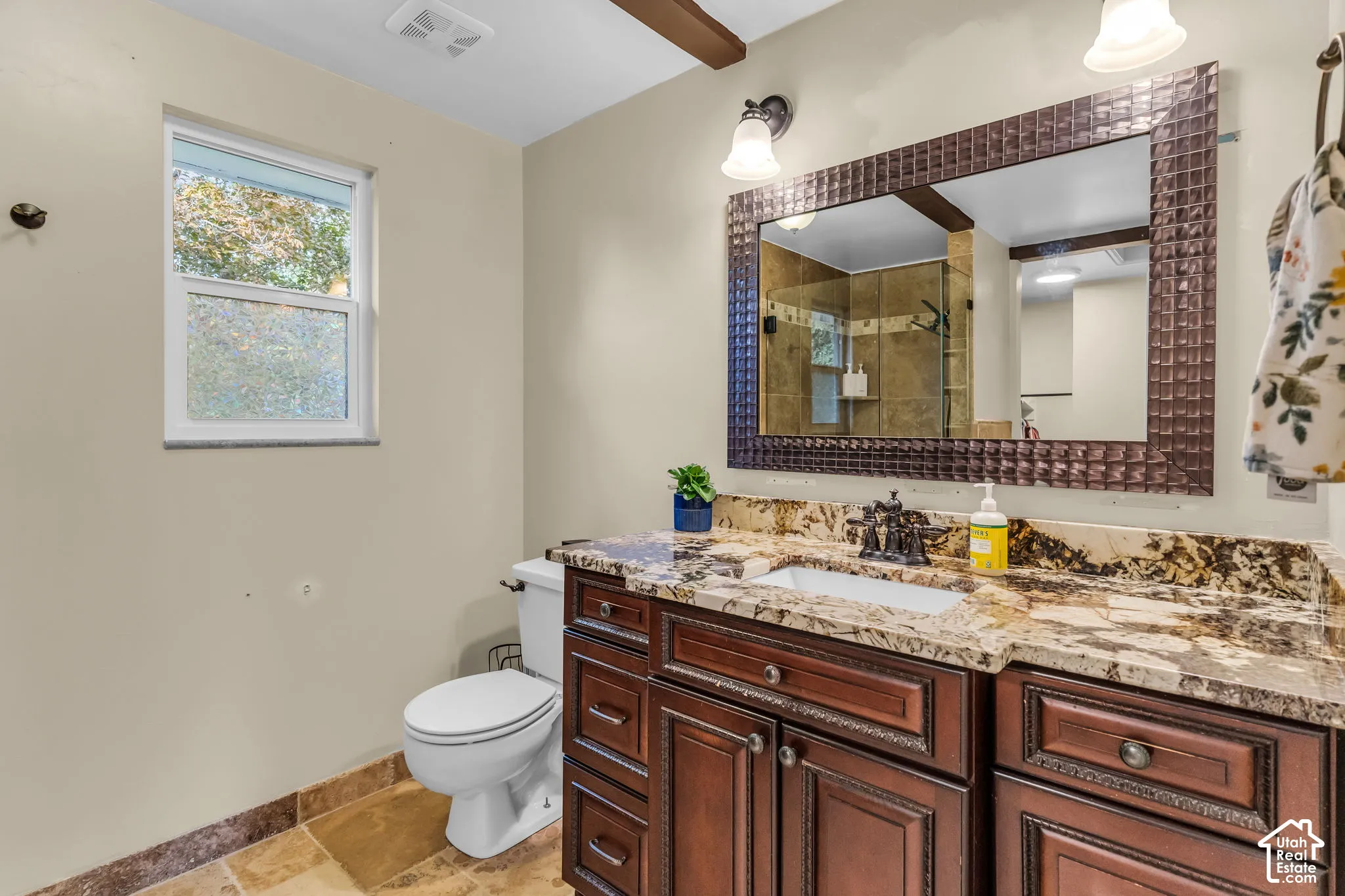 Vanity with an integrated sink, decorative framed mirror, and dual light fixtures