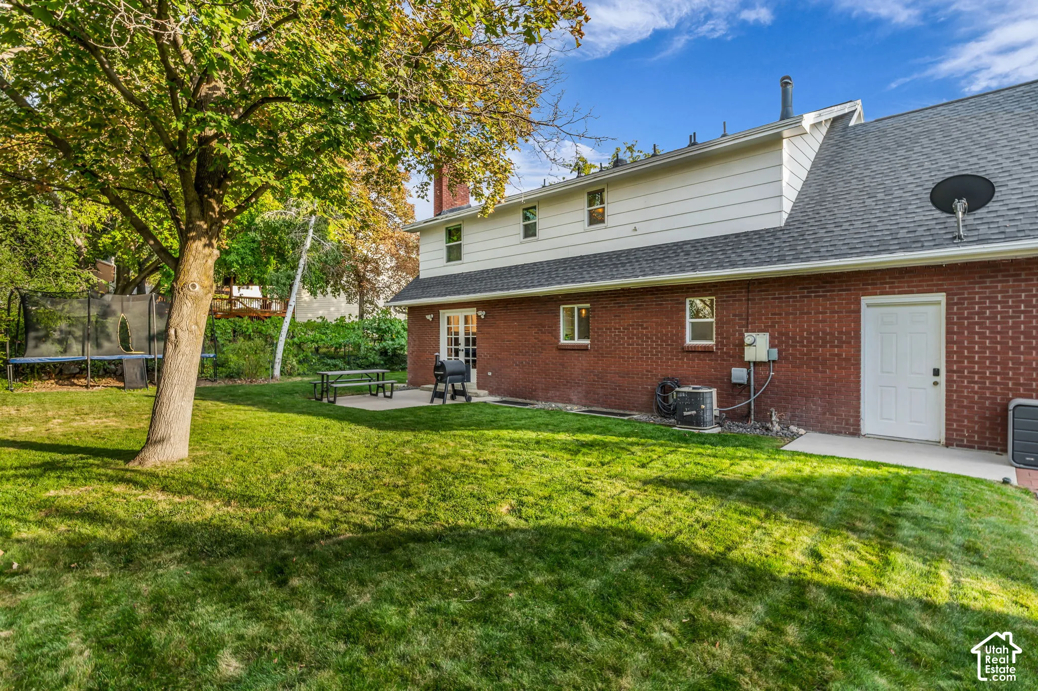 Expansive lawn with mature trees and a concrete patio