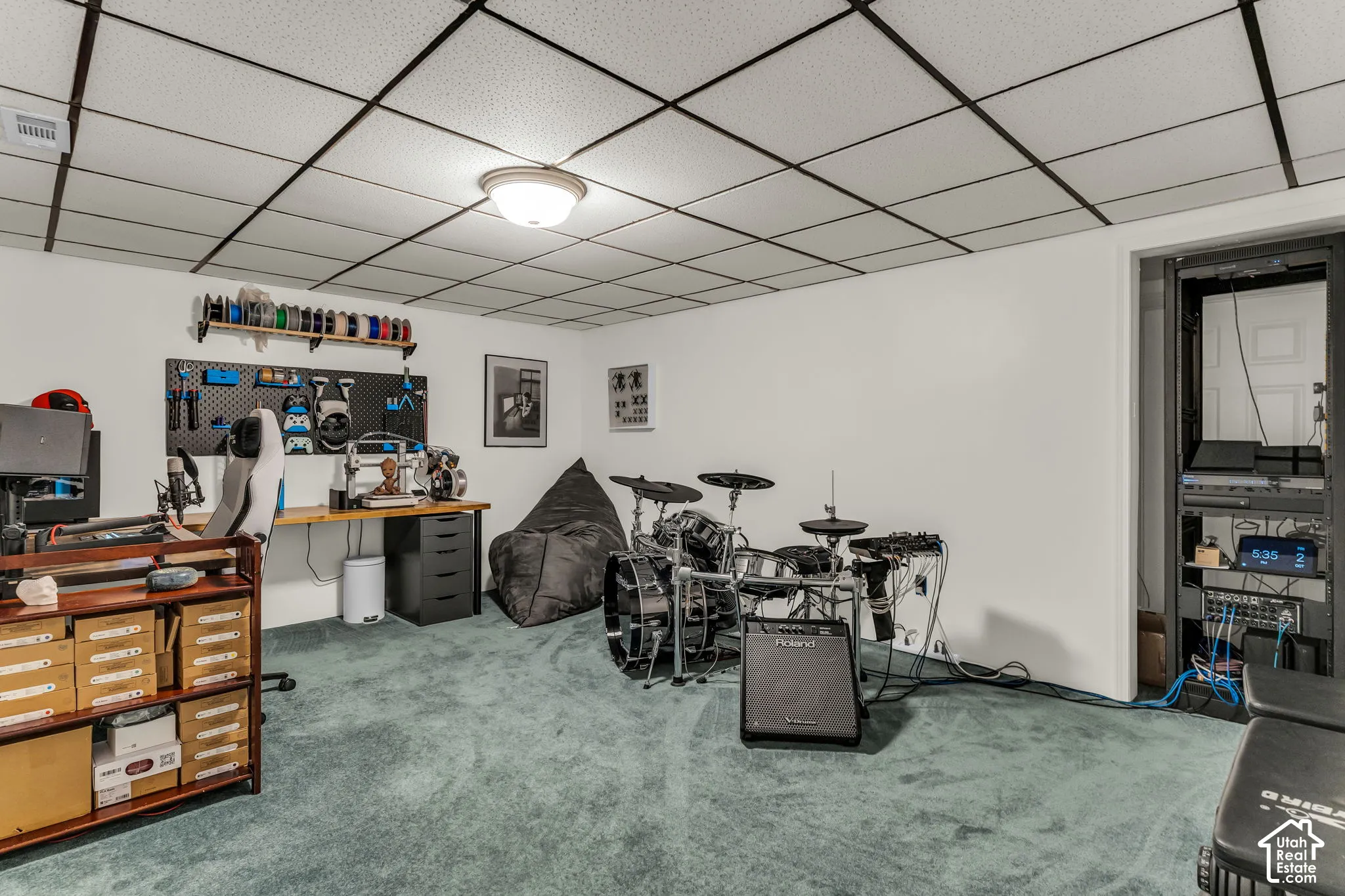 White walls with a drop ceiling, featuring recessed lighting, and a built-in workstation with shelving