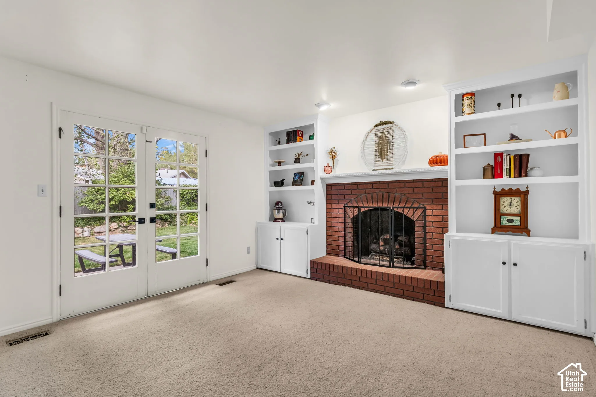 Brick fireplace with hearth, flanked by built-in shelving and lower cabinetry