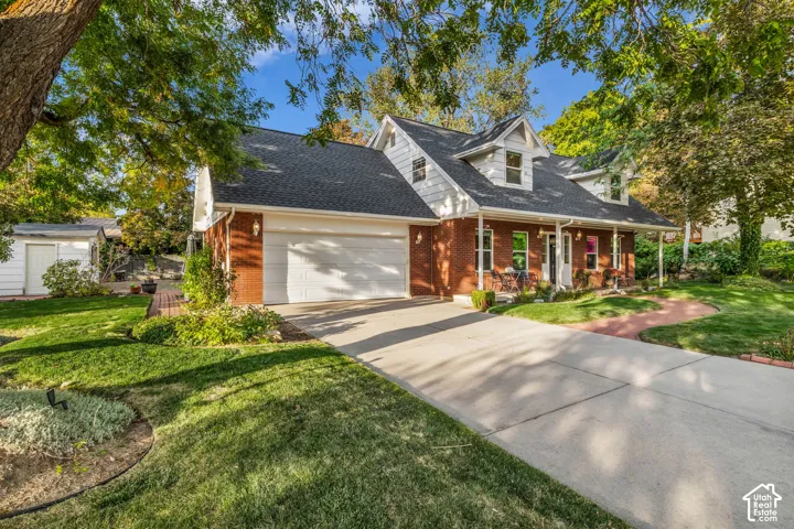 Brick facade residence featuring a covered front porch, dormer windows, and an attached two-car garage