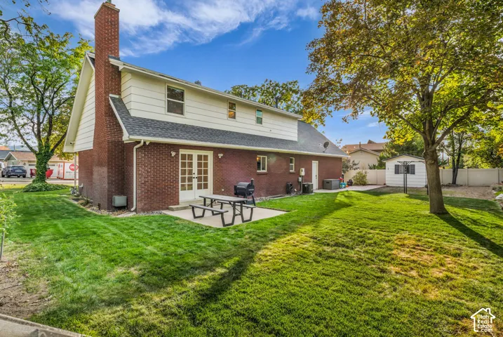 Rear exterior featuring brick and siding finishes, a prominent brick chimney, and a concrete patio