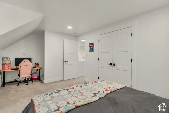 Recessed lighting, white paneled doors with black hardware, and gray carpeting