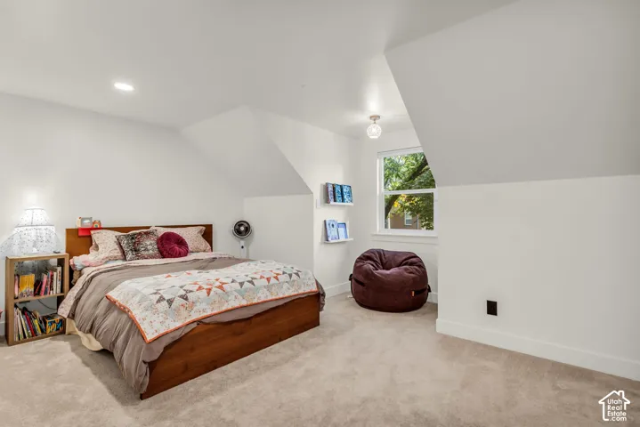 Carpeted room with sloped ceilings, recessed lighting, and a large window