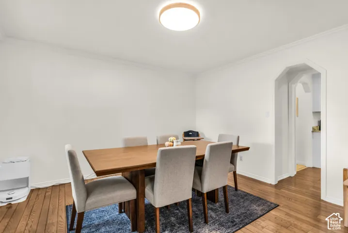 Hardwood flooring, crown molding, arched entryway, and a flush mount ceiling light fixture