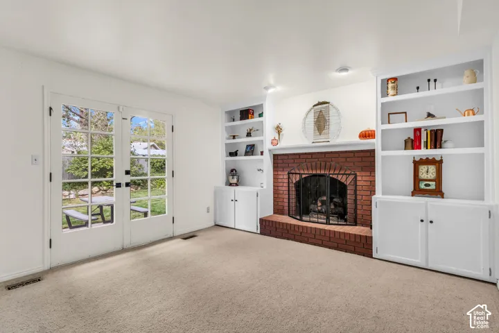 Brick fireplace with hearth, flanked by built-in shelving and lower cabinetry