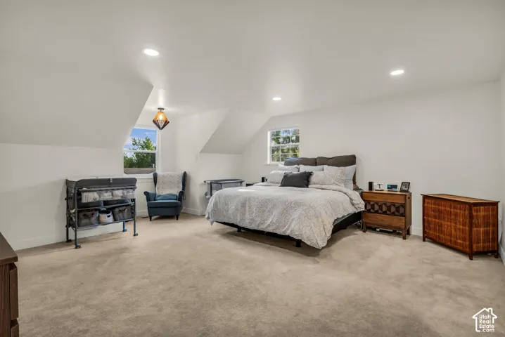 Vaulted ceiling, recessed lighting, carpet flooring, multiple windows, and a geometric pendant light fixture