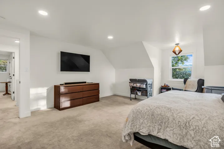 Recessed ceiling lighting, white walls, angled ceilings, window with exterior scenery, and a modern geometric pendant light fixture