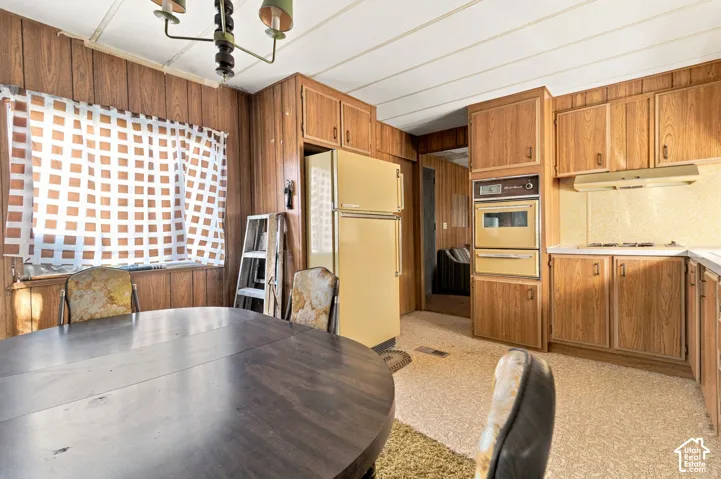 Wood-paneled walls with built-in cabinetry, dual wall ovens, an integrated range, and a two-door refrigerator