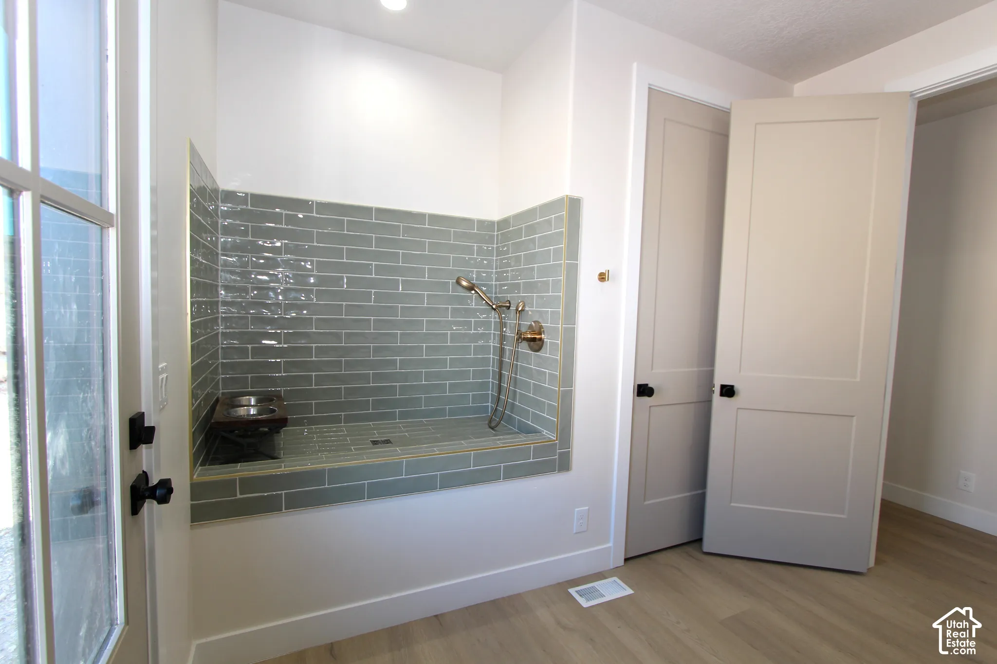 Built-in pet shower featuring subway tile, handheld shower fixture, and a glass-paneled door