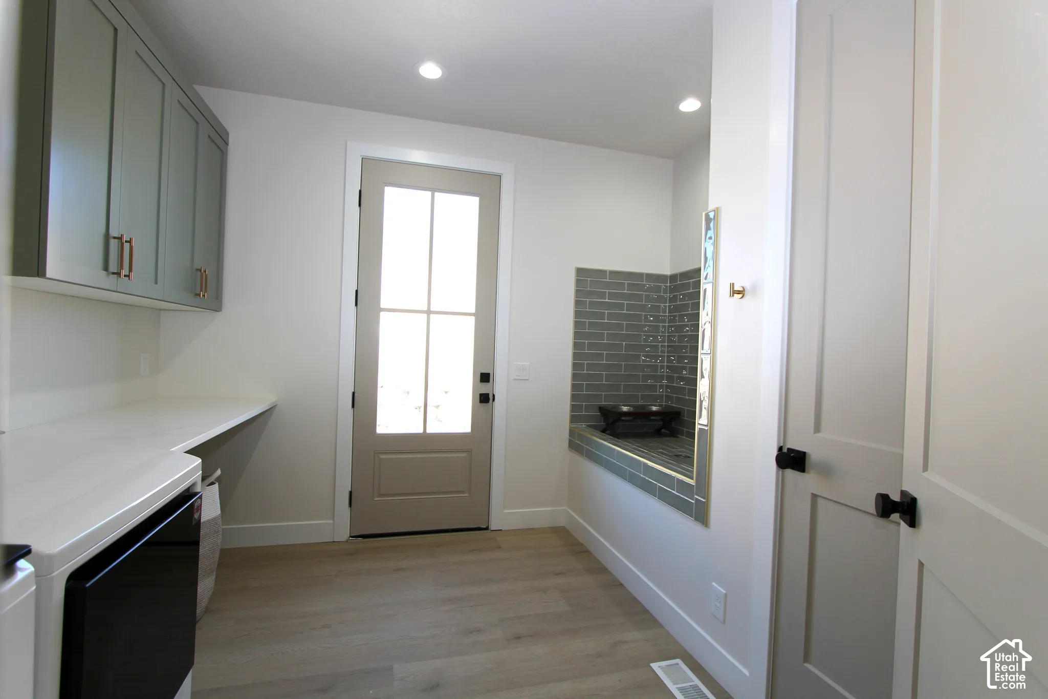 Light-toned wood-finish flooring, recessed lighting, built-in cabinetry, and a tiled built-in bench