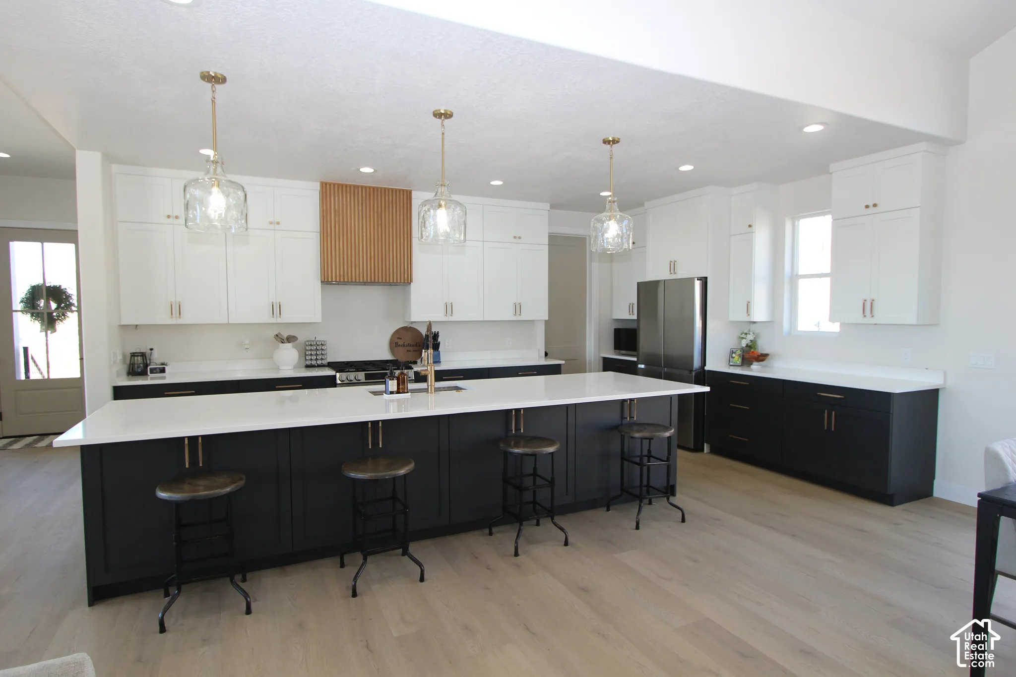 Expansive kitchen featuring an oversized island with countertop seating, a two-tone cabinetry design, wood-finish flooring, and recessed lighting