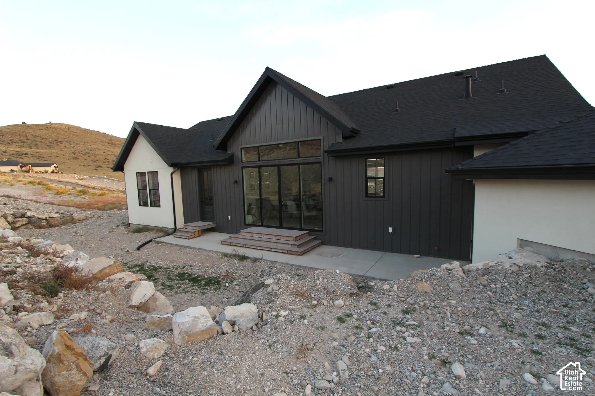 Contemporary exterior featuring dark board-and-batten siding, light stucco accents, and a dark shingle roof
