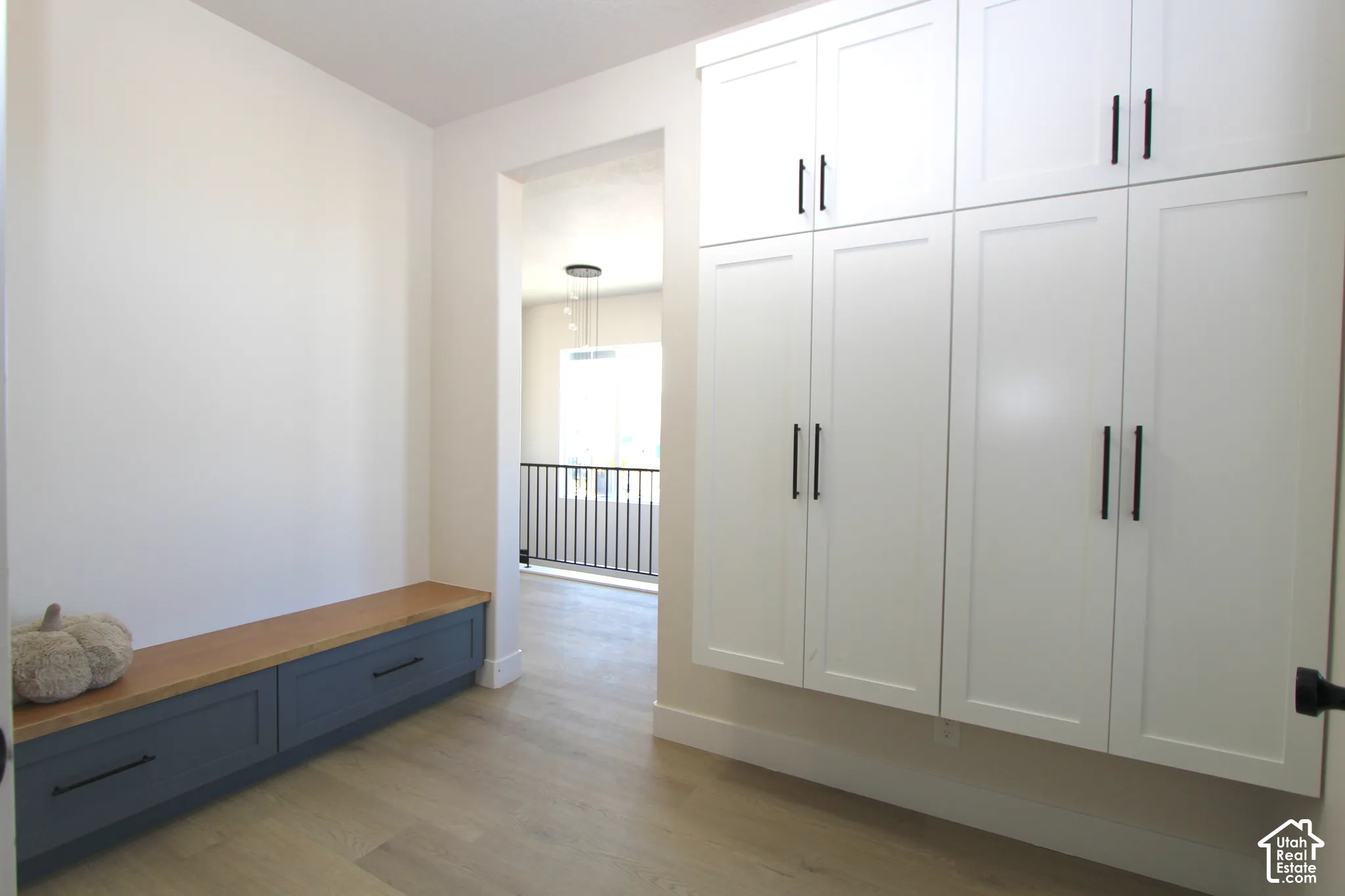 Built-in storage cabinetry with matte black hardware, built-in bench with wood-finish top, and light wood-finish flooring