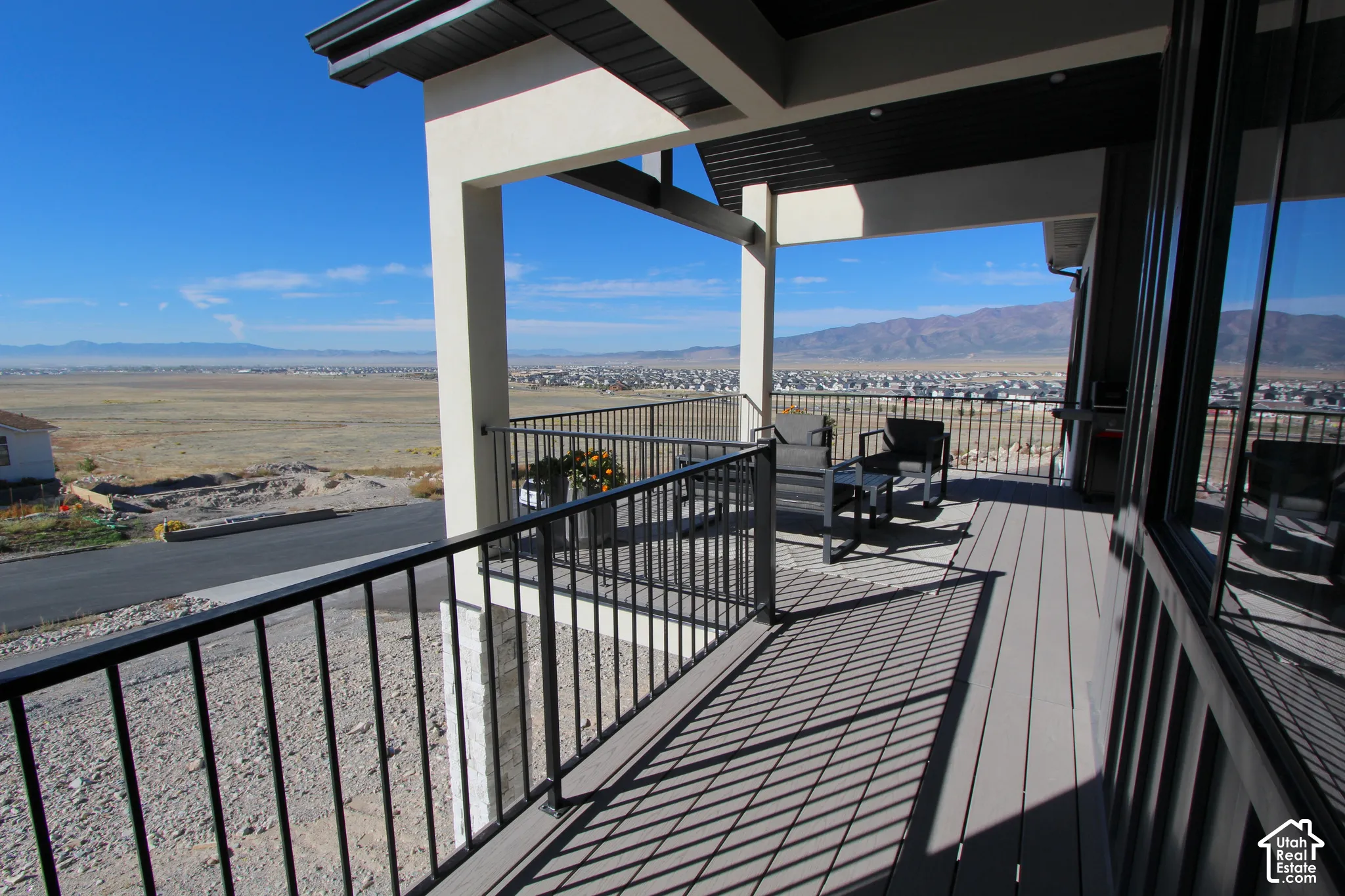 Expansive covered deck featuring a durable composite surface, black metal railings, and stucco columns