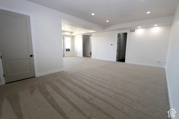 Expansive room featuring plush carpeting, recessed lighting, and a tray ceiling