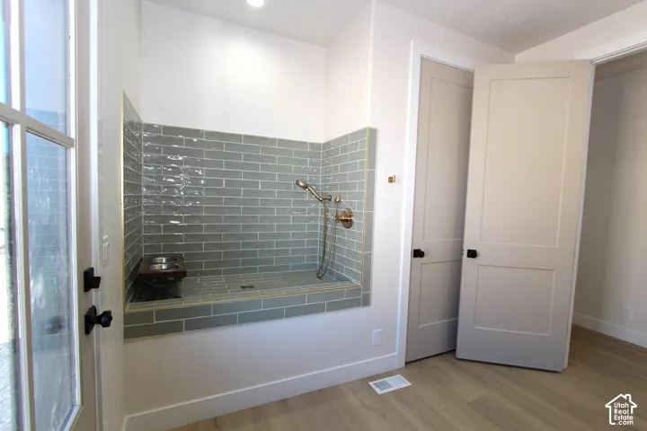Built-in pet shower featuring subway tile, handheld shower fixture, and a glass-paneled door