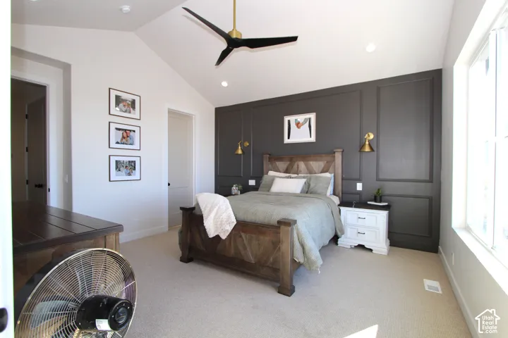 Vaulted ceiling, recessed lighting, accent wall with panel molding, carpet flooring, and a ceiling fan with integrated lighting