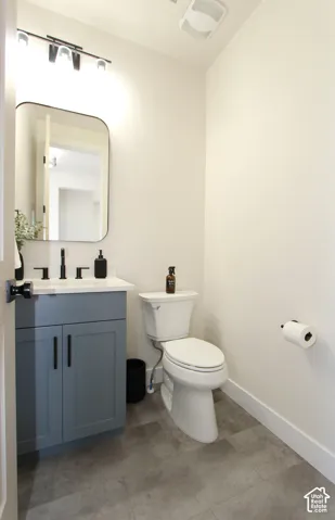 Powder room with a blue-gray vanity, white countertop, black fixtures, and a rectangular mirror