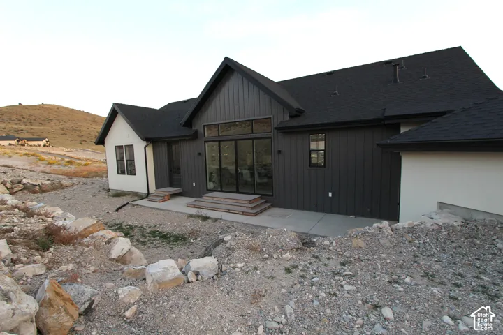 Contemporary exterior featuring dark board-and-batten siding, light stucco accents, and a dark shingle roof