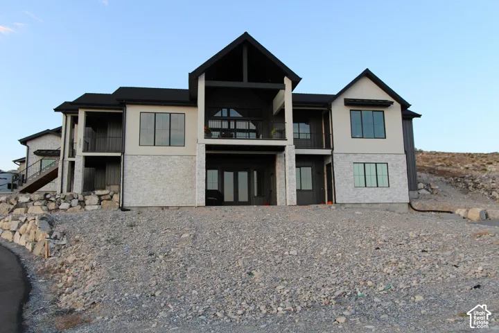 Multi-level exterior with light-toned stucco and contrasting dark vertical siding