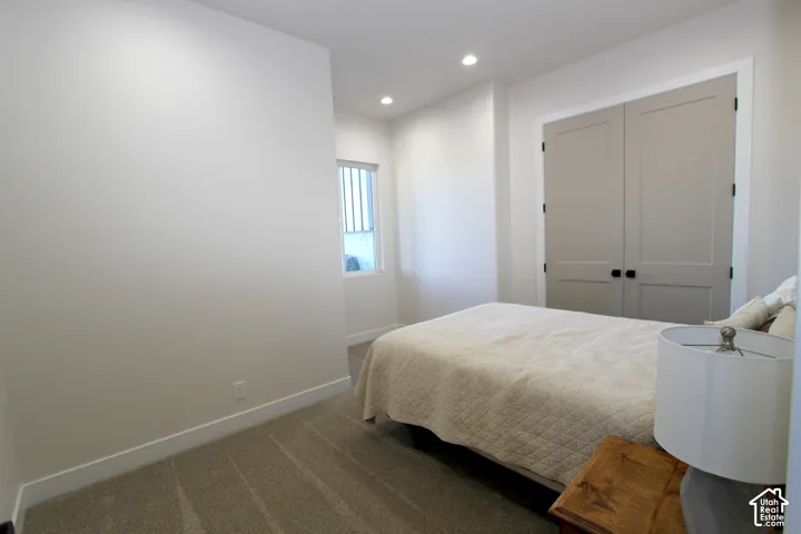 Recessed ceiling lights, textured carpet flooring, painted shaker-style doors, and a window with horizontal blinds