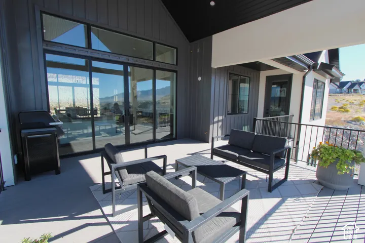 Expansive covered patio featuring a black metal railing, board and batten siding, and large sliding glass doors with transom windows
