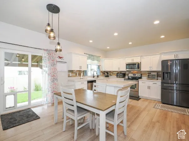 Kitchen featuring white cabinetry, stainless steel appliances, recessed lighting, a central island, and wood-finish flooring