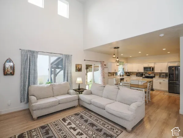 Vaulted ceilings with high windows, wood-finish flooring, white cabinetry, stainless steel appliances, and a glass sliding door