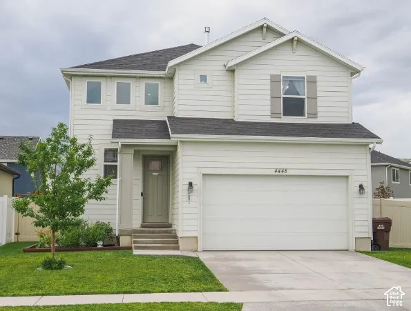 Two-story residence featuring light-colored siding, a dark shingle roof, a two-car garage, and an inviting entryway with a light-colored door