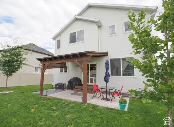 Stucco exterior with multiple windows, concrete patio, and a wood pergola