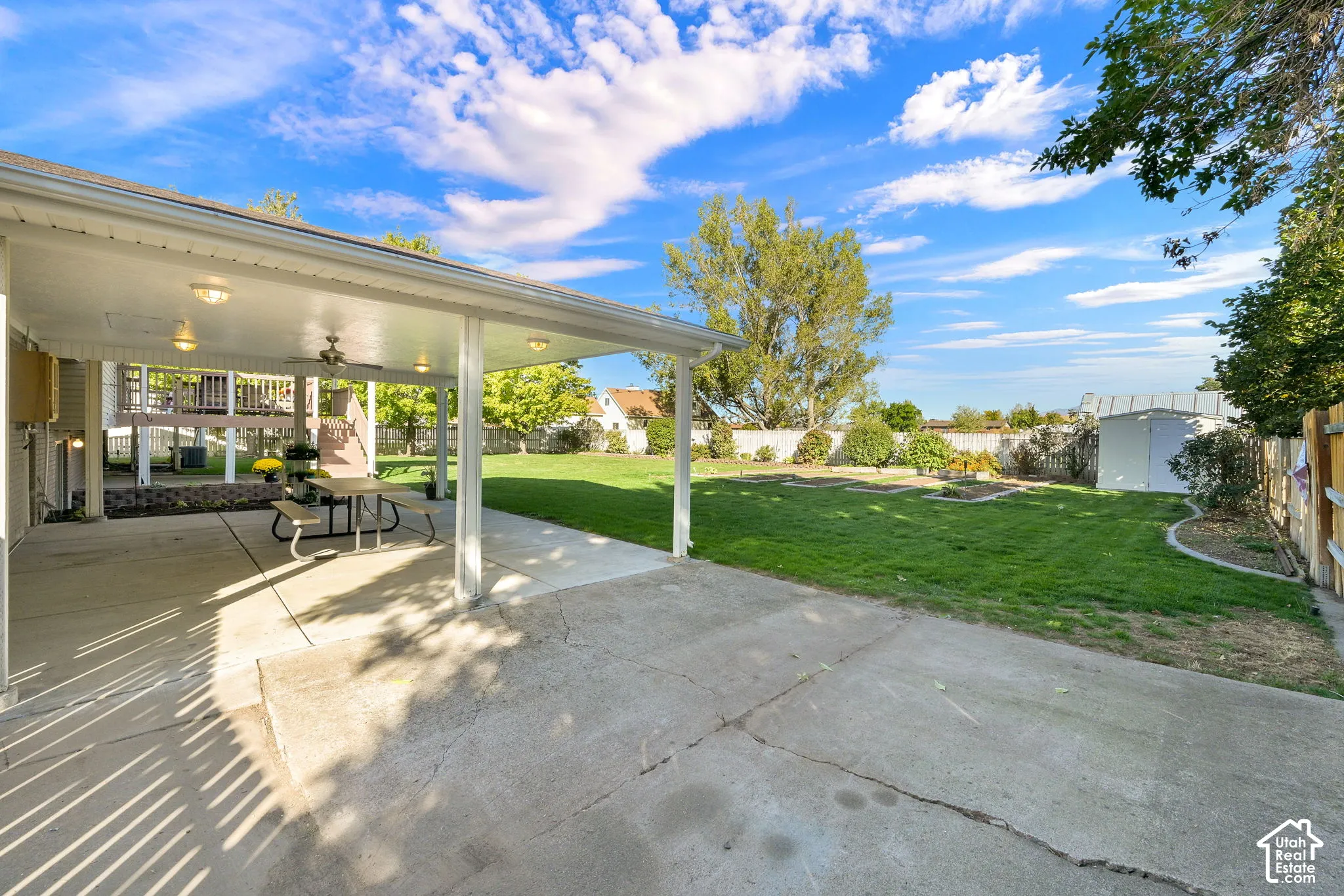 Expansive concrete patio with a covered section, integrated ceiling fan, and recessed lighting