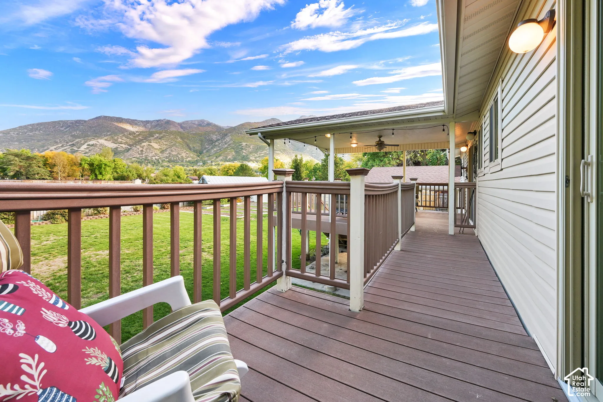 Deck from sliding door in primary bedroom with composite decking and brown railings, connected to  a covered portion of deck off dining roomwith ceiling fan