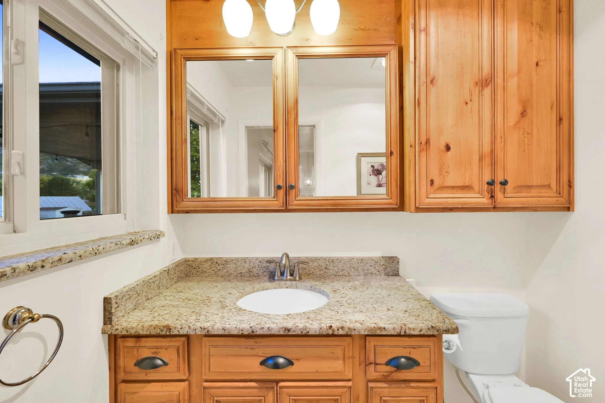 Primary bathroom. Wood-finish vanity with a granite countertop, undermount sink, and chrome faucet