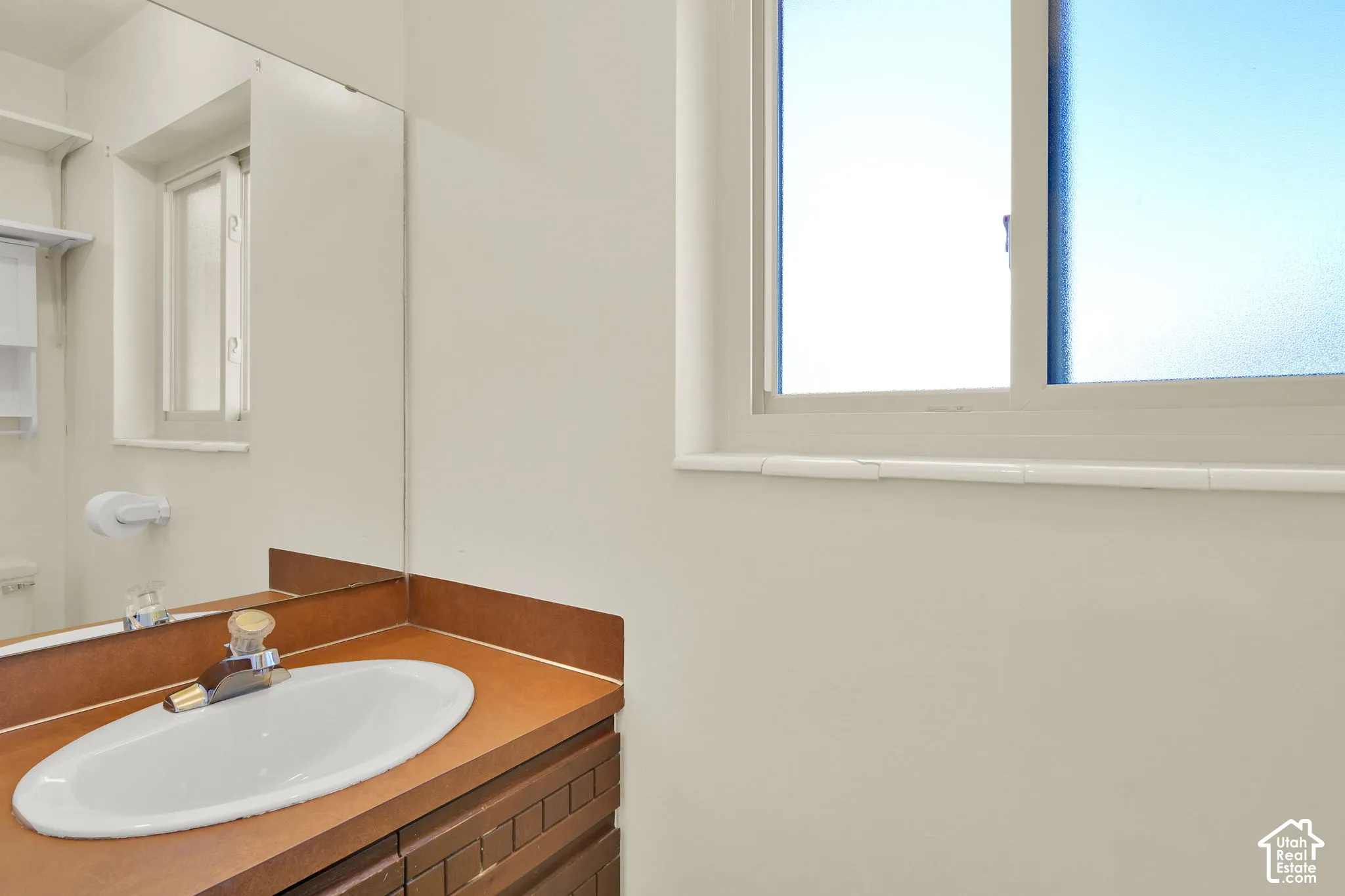 1/2 bath- Mudroom between garage and kitchen with built-in vanity with an oval basin sink, wall-to-wall mirror, and window