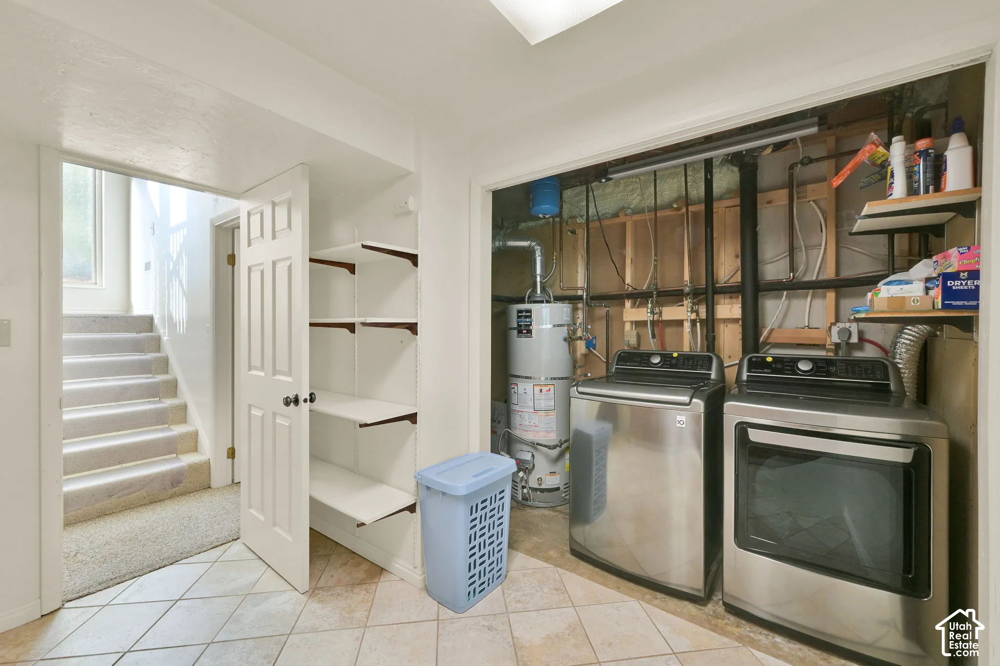 Tiled flooring, built-in shelving, water heater, and an open stairwell with carpeted steps