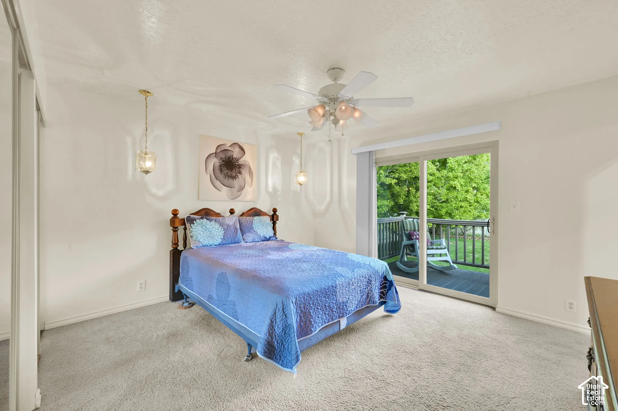 Primary bedroom. Plush carpeted flooring, a ceiling fan with integrated lighting, and a sliding glass door leading to an outdoor deck