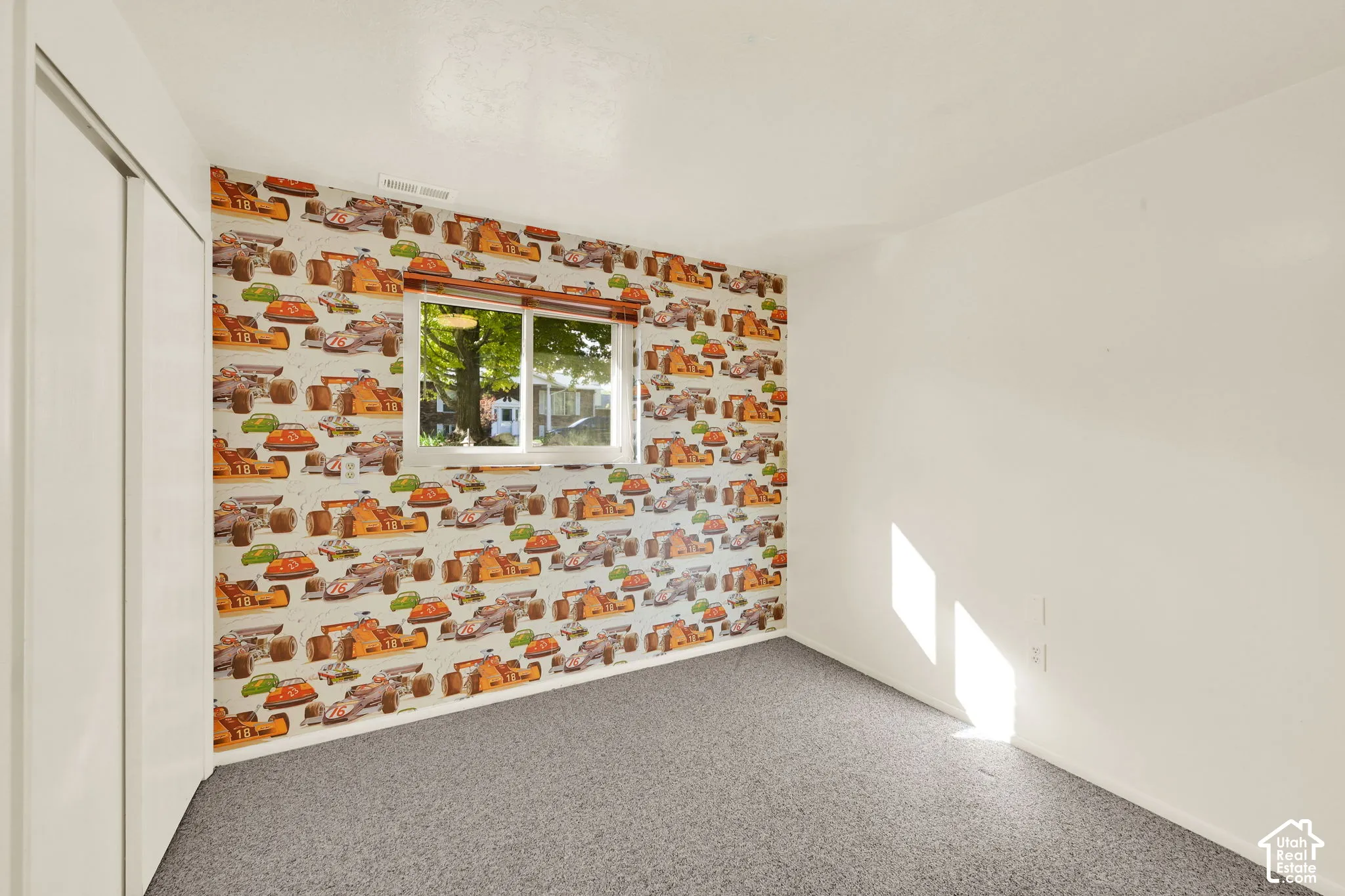 Bedroom 4. Carpeted room featuring a white-framed window, car wallpaper,, and a white closet with sliding doors