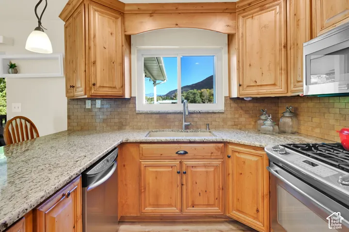 Wood-finish cabinetry, light-toned countertops, tile backsplash, and stainless steel appliances