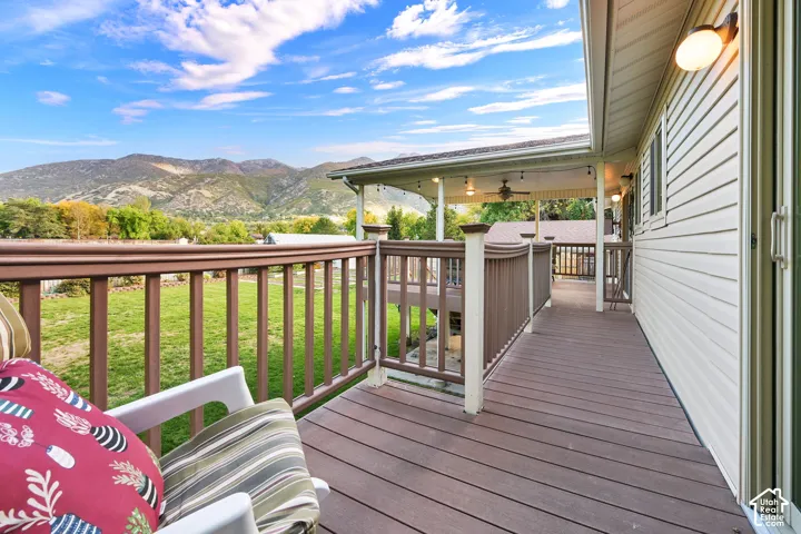 Deck from sliding door in primary bedroom with composite decking and brown railings, connected to  a covered portion of deck off dining roomwith ceiling fan