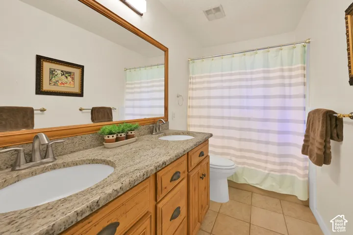 Upstairs full bath. Double vanity with integrated sinks, granite countertop, wood-finish cabinetry, and brushed nickel faucets