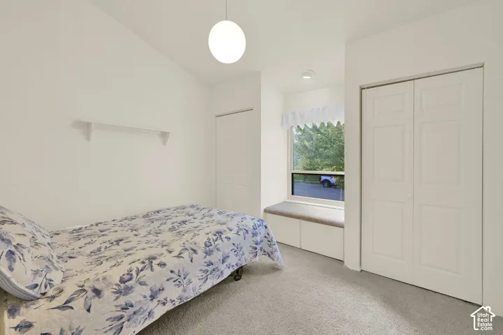 Bedroom 2. Built-in window bench with integrated storage, neutral carpeting, and bi-fold closet doors